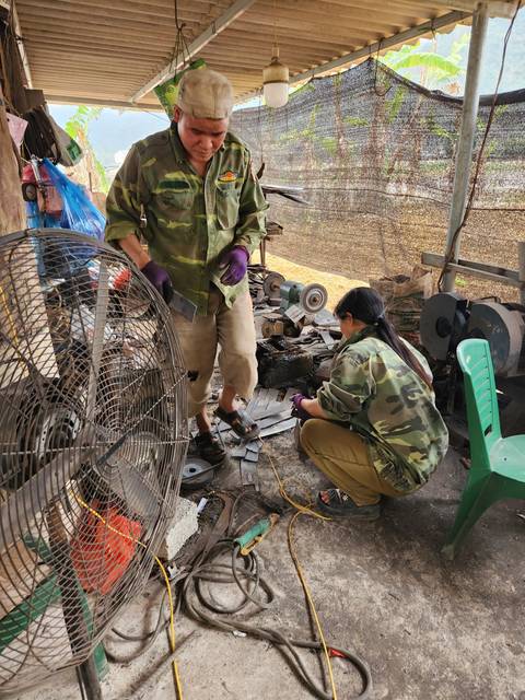       People working with tools in an open workspace.
  