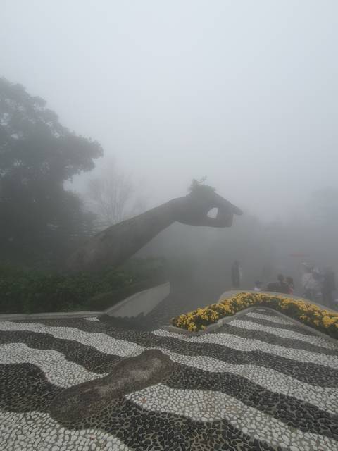 A misty scene with a sculpture and flowers.