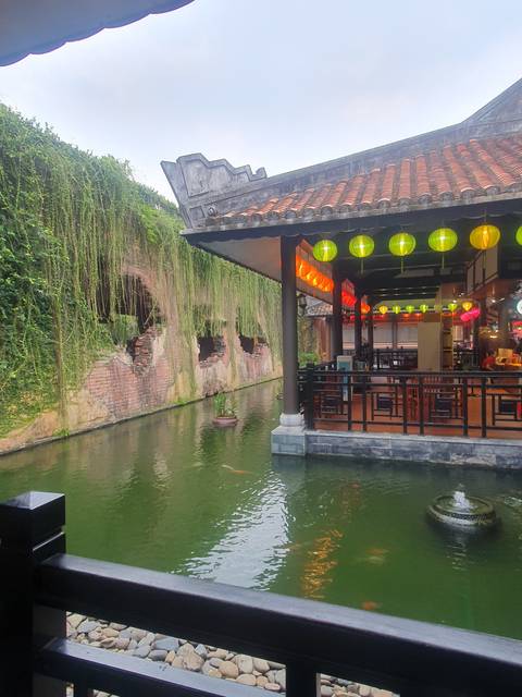 A riverside view with a building and colorful lanterns.