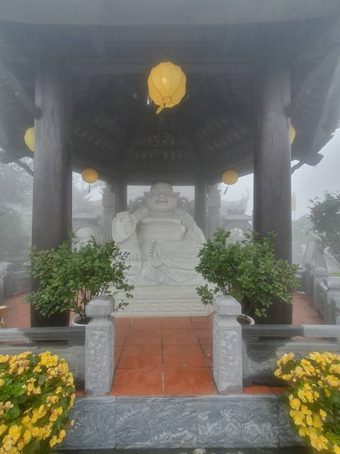 A Buddha statue in a foggy pavilion.