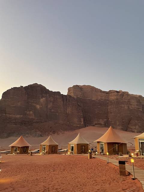       Luxury camping tents set amidst large rock formations in a desert terrain.
  