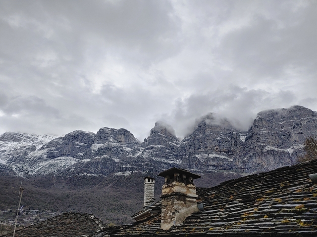       Mountainous landscape with snow and clouds.
  