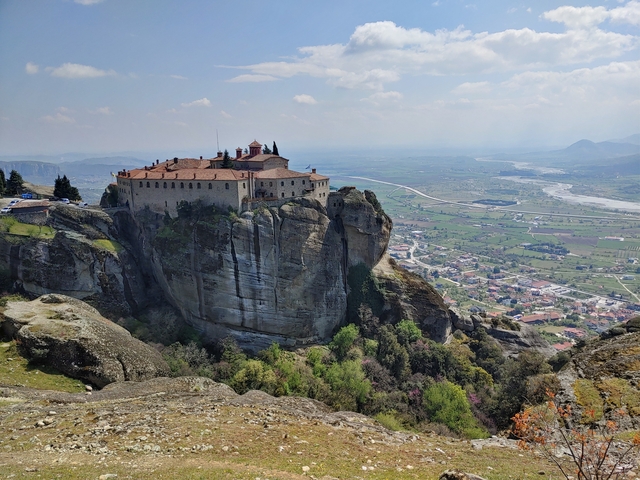       Meteora monastery perched on a rock with a view of the valley.
  