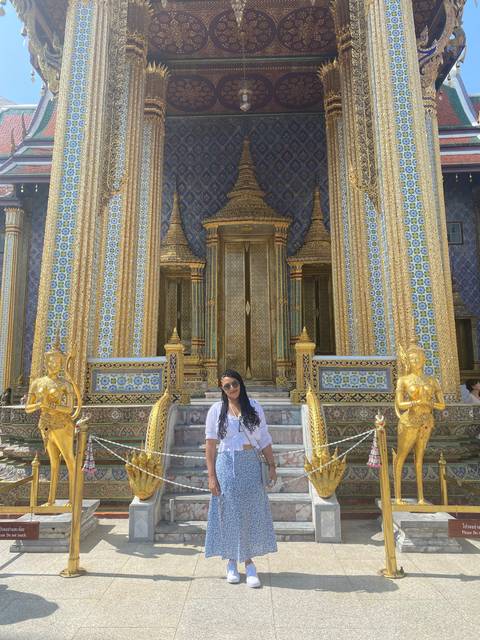       Person standing in front of a golden temple entrance.
  