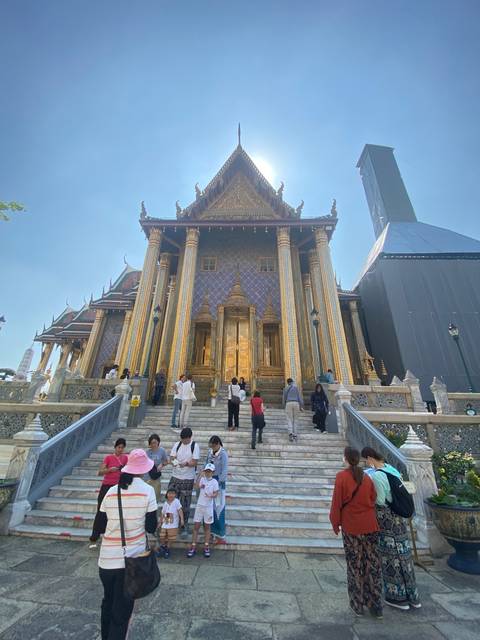 People at a temple with gilded structures and steps.