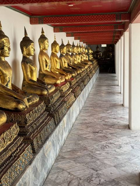 Row of golden Buddha statues in a temple.
