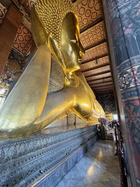       Large reclining gold Buddha statue in a temple.
  
