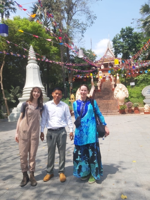       Three people standing in front of a temple with blurry focus.
  