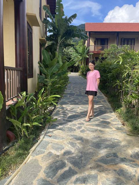 A person standing on a stone pathway surrounded by greenery.
