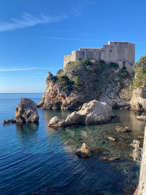 Rocky coastal view with a historic fortress.