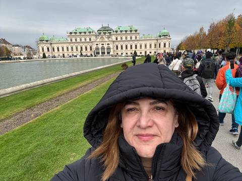A person bundled in winter clothing with a historic building behind.