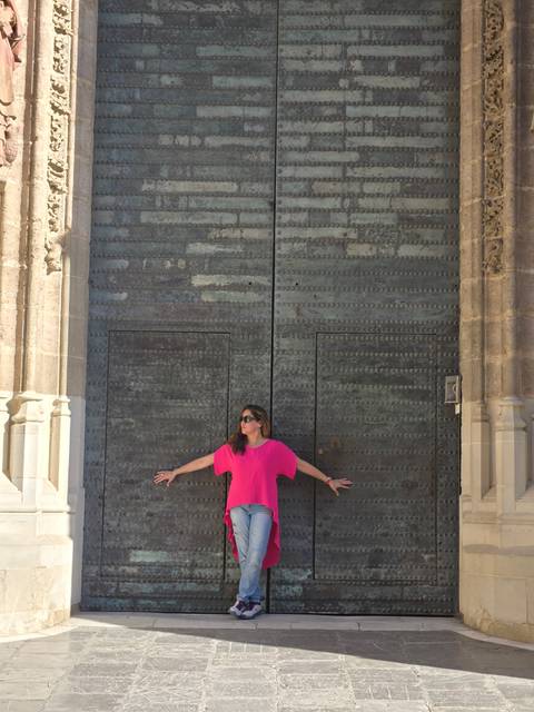       A person posing against a large ornate door.
  
