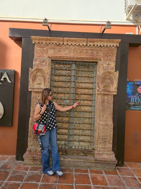       A person posing by an intricately carved door.
  