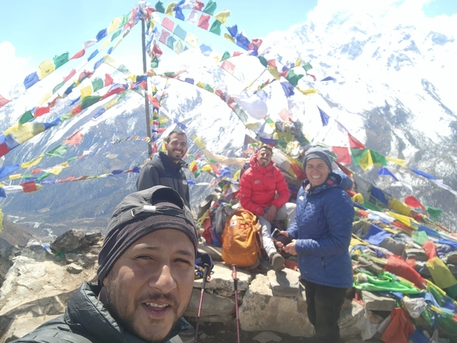 Group of people with prayer flags in a mountainous region.