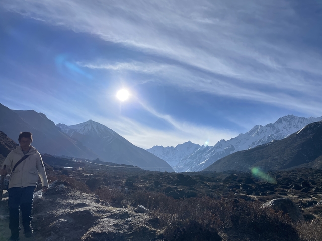 Person in a mountainous valley with the sun shining brightly.