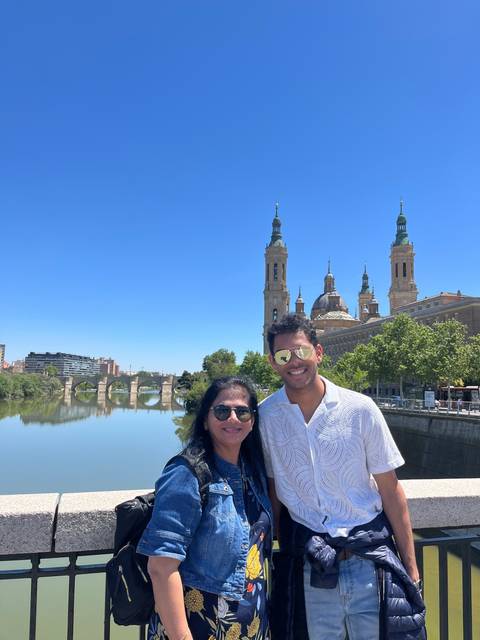       Couple posing in front of a cityscape with a river.
  
