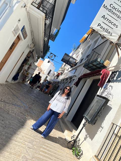      Person standing on a narrow street with shops.
  