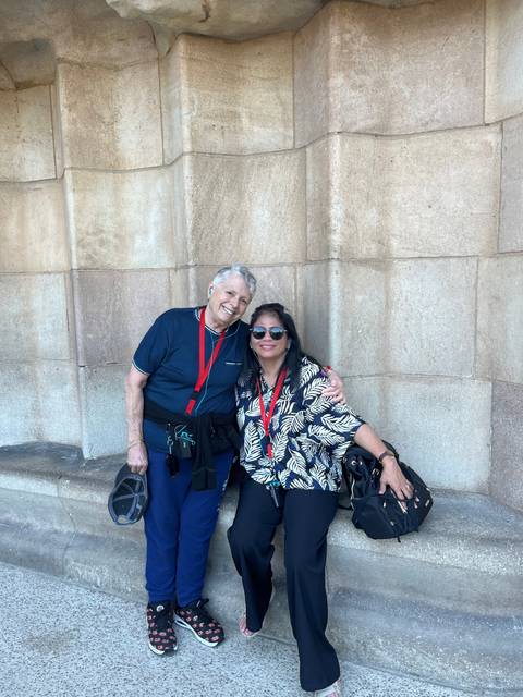      Two people sitting together in front of a stone wall.
  