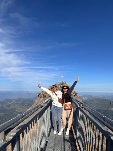       Two people posing on a bridge with a scenic view.
  