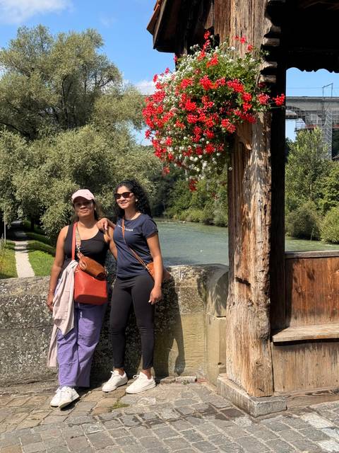       Two people posing by a traditional Swiss structure.
  