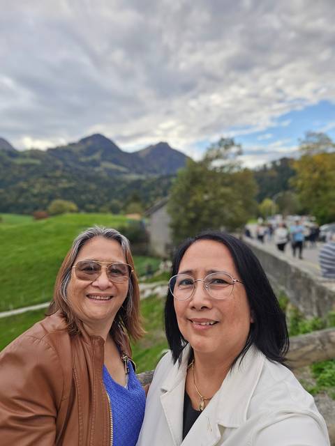 Two people posing with hills and sky in the background.