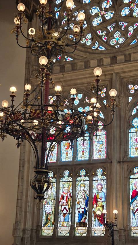       Interior of a cathedral with chandeliers and stained glass.
  
