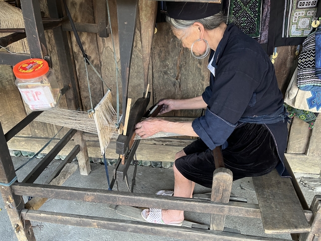 A person sitting at a traditional loom working.