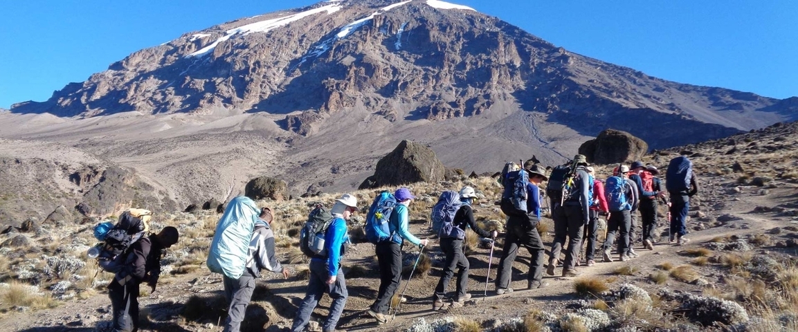 Group of hikers climbing a mountain under a blue sky.