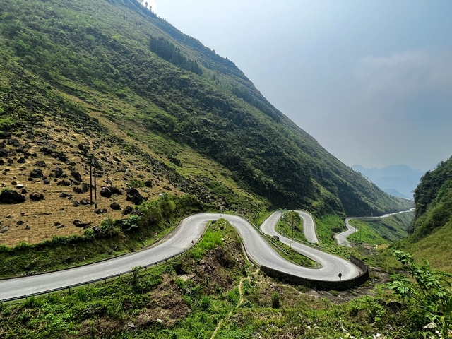       Winding road through hilly terrain with a motorbike.
  