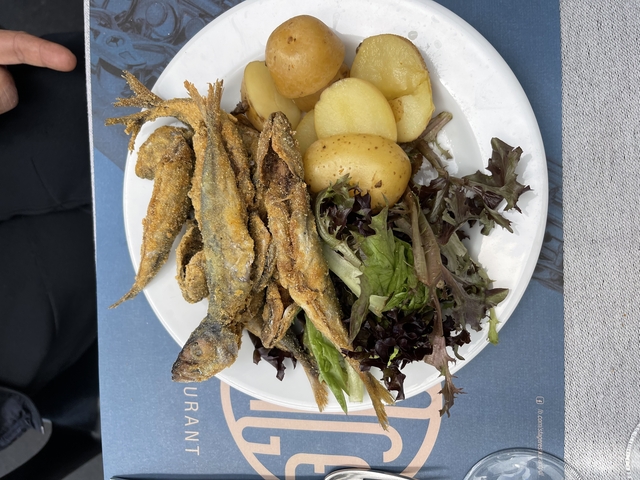       Fried fish on a plate with potatoes and salad.
  