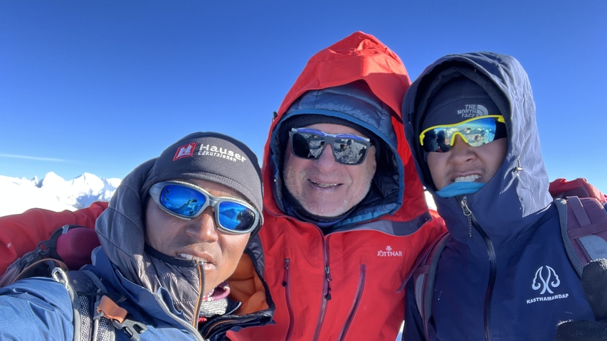       Three people in mountain climbing gear posing.
  