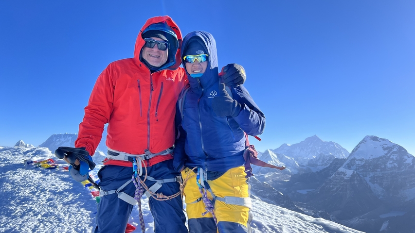       Two people posing on a snowy mountain peak.
  