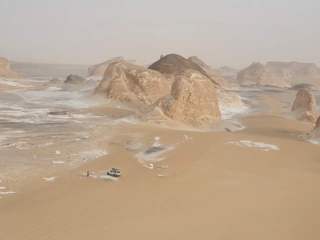 Desert landscape with unique rock formations and a car.
