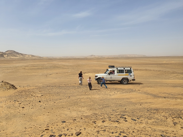 Desert terrain with people and a vehicle.