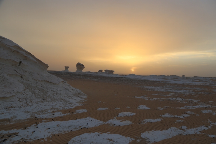 Sunset view over a desert with sand dunes.
