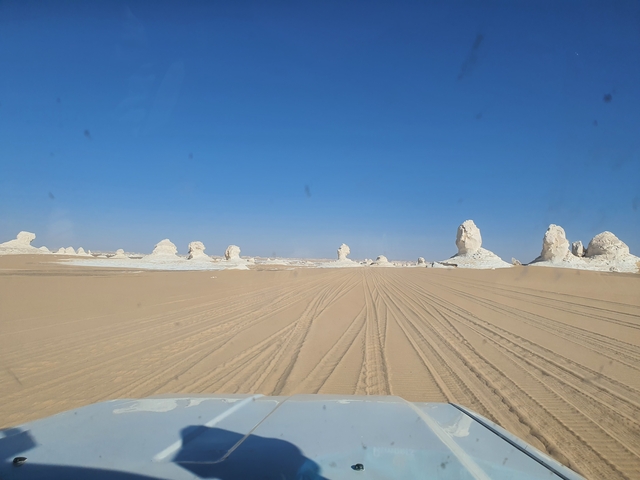 Road leading through a desert with rock structures.