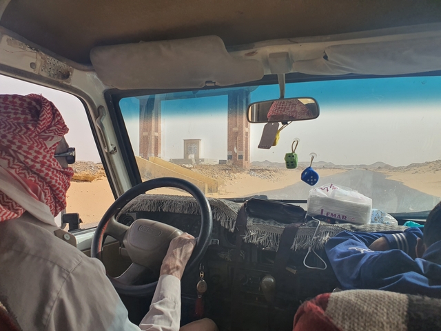 Interior view of a car driving through a desert gate.