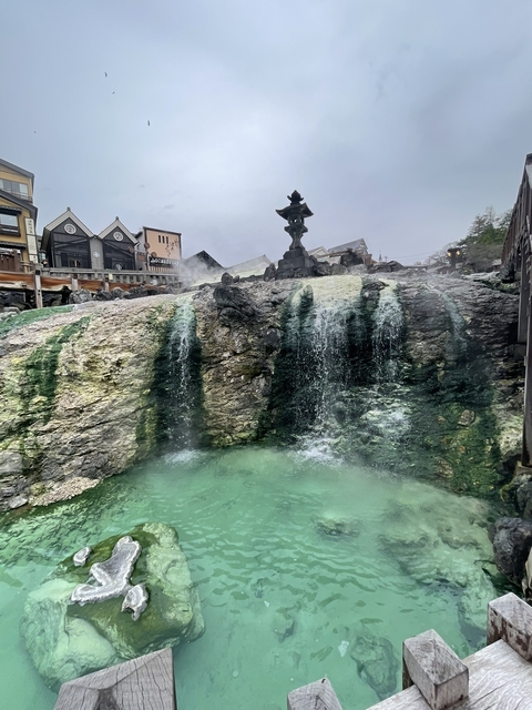 Hot spring with steaming water and nearby buildings