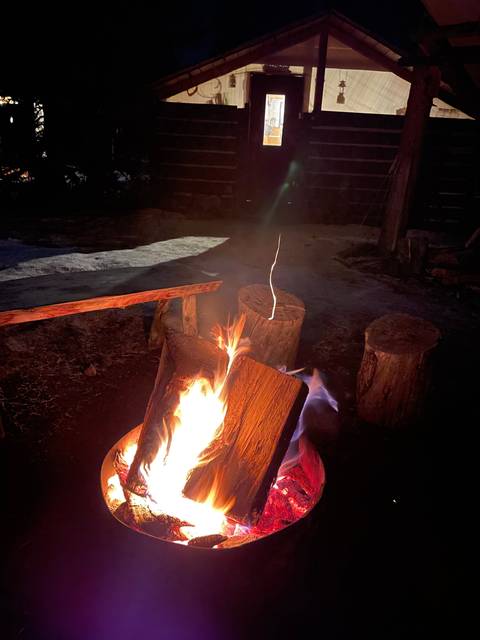       Campfire in front of a cabin at night.
  