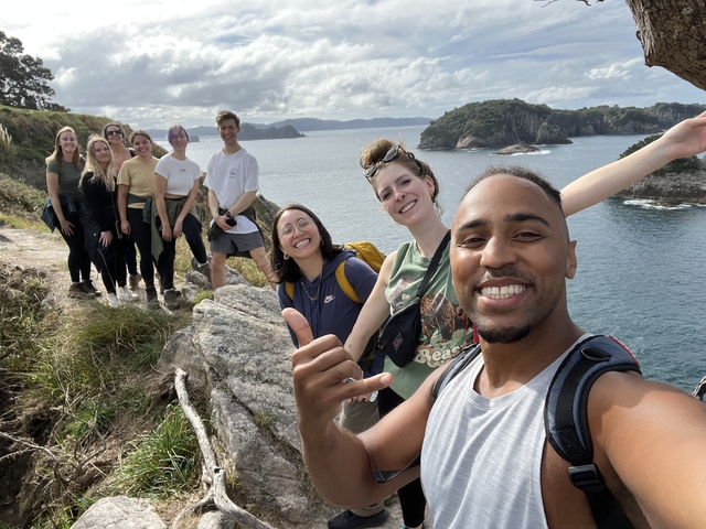 A group of people posing on a cliff with a scenic ocean view.