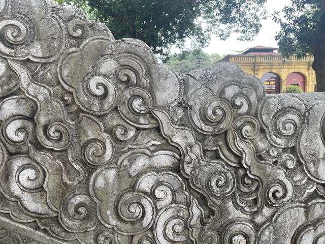 Close-up of intricate stone carvings with a yellow building in the background.