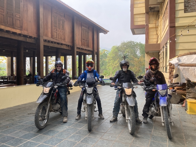 Four motorcyclists posing in front of a building