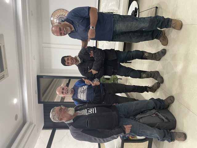       Four men posing in a room with a white background.
  