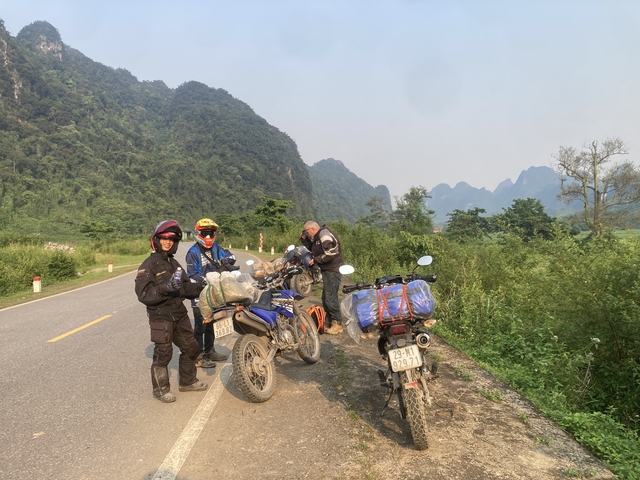 Group of motorcyclists on a road with limestone mountains