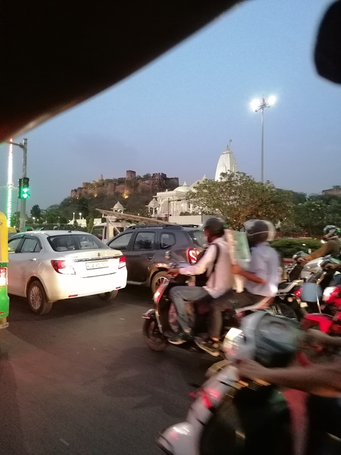 City traffic with a temple and fort in the background