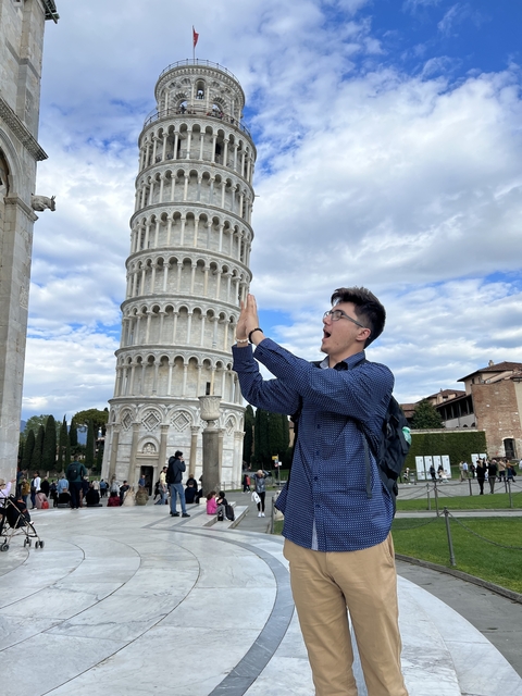 Person playfully posing with the Leaning Tower of Pisa