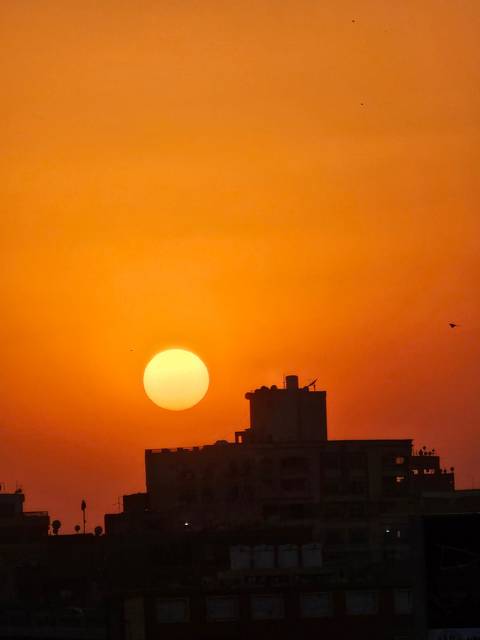Sunset view with silhouette buildings and orange sky.