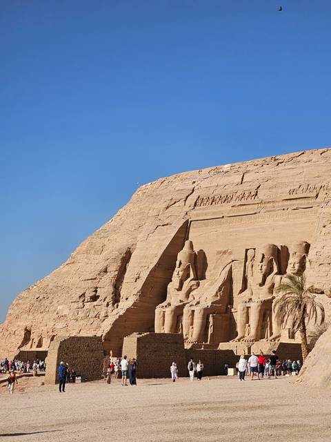       Abu Simbel temple with colossal statues and tourists.
  