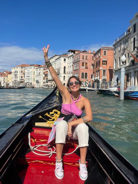 A person posing on a gondola in Venice.