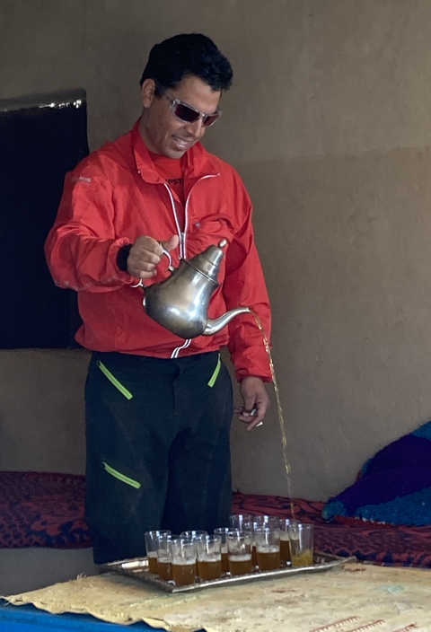       Person pouring tea from a silver teapot.
  
